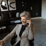 An Elderly Woman in Gray Coat Sitting while Talking on the Phone