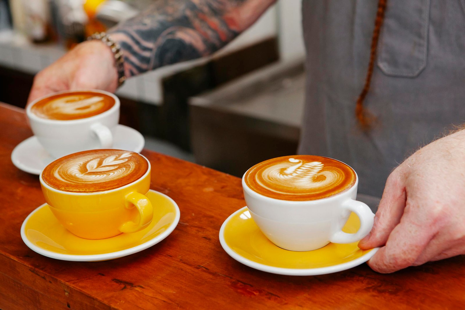 Crop barista with cups of delicious coffee in cafe