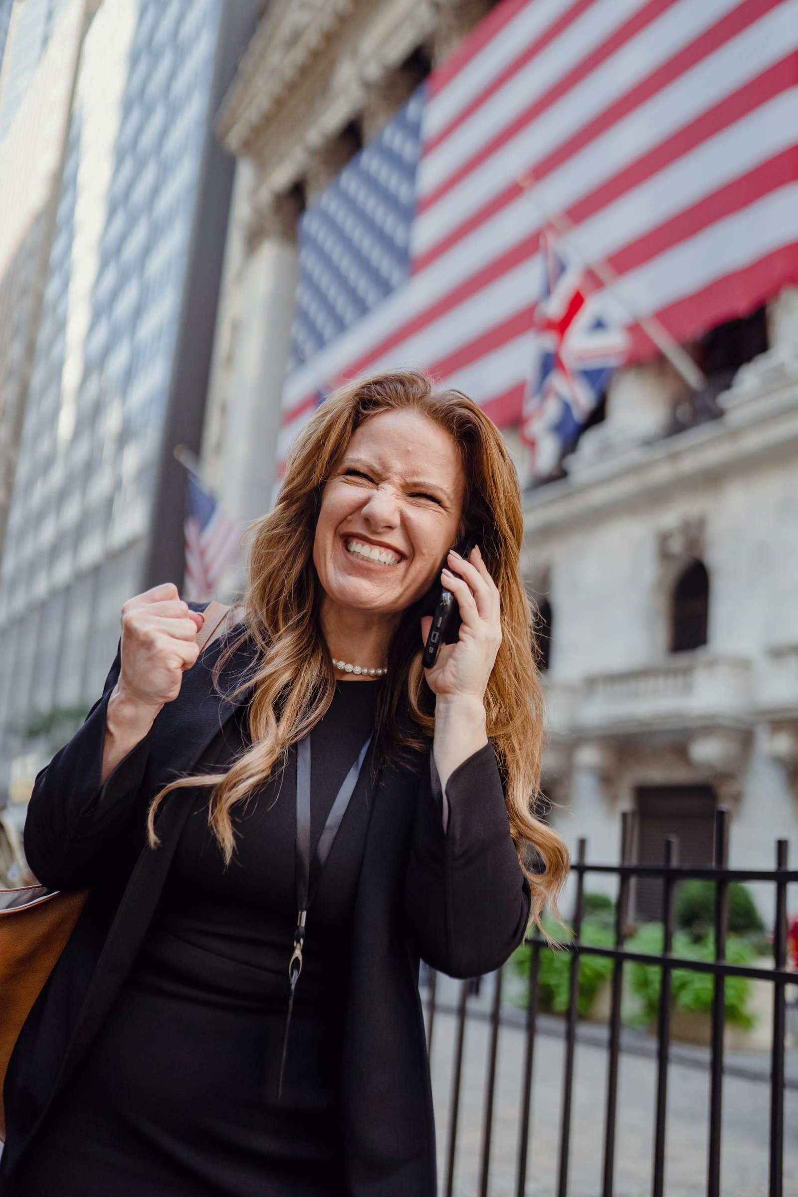 Excited Woman Using Mobile Phone on a Street and US Flag in Background