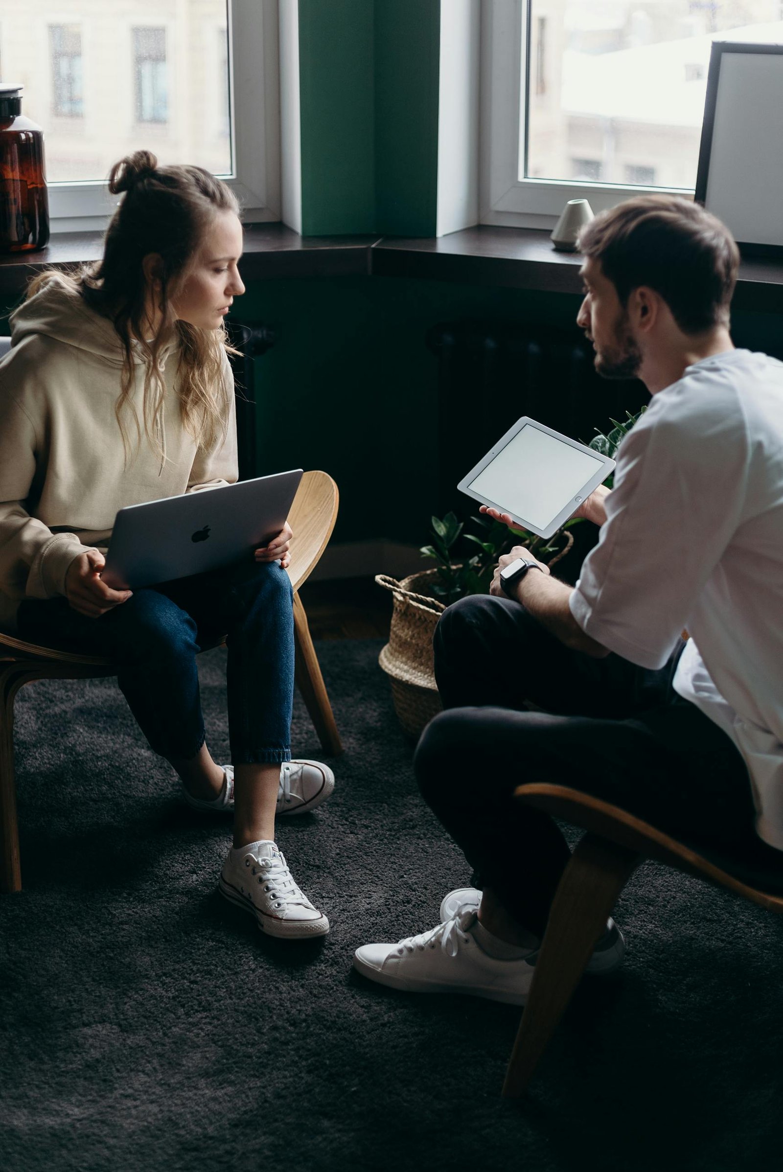 Photo of Couple Talking While Holding Laptop and Ipad