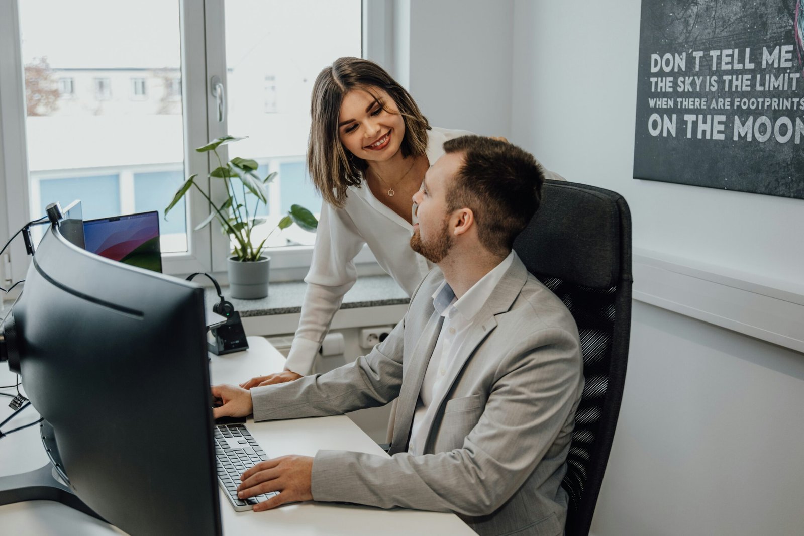 a man and a woman sitting at a desk in front of a computer