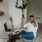 A Man Sitting on a Chair Rubbing His Eyes