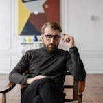 Man in Black Sweater Sitting on Brown Wooden Chair