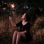 Woman Holding Sparkler While Sitting Down